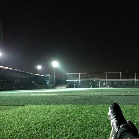 A floodlit football pitch at night, seen from the bleachers