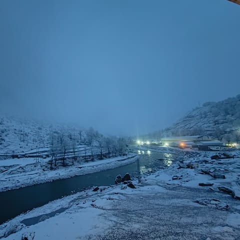 Mountain valley at dawn with a river running through snow